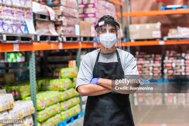 megastore employee wearing a protective face mask and a face shield - supermarket covid stock pictures, royalty-free photos & images