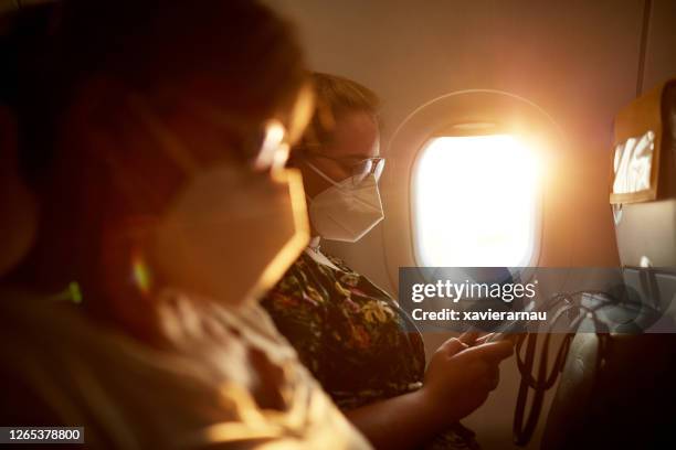 female travelers wearing kn95 masks on airplane - máscara de proteção imagens e fotografias de stock