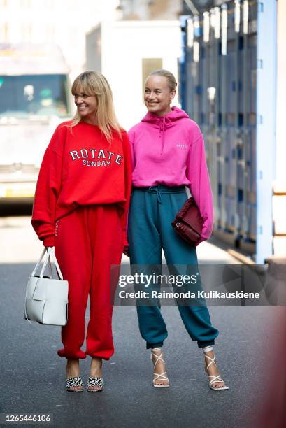 Jeanet Madsen wearing red sweatpants, high-heels and a jamper and Thora Valdimars wearing blue sweatpants, high-heels and pink jamper outside...