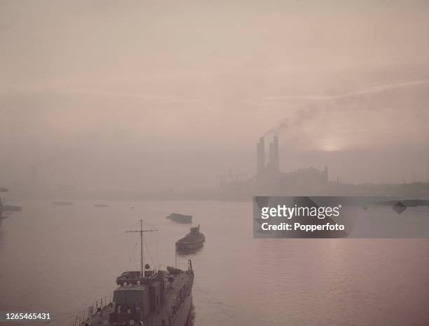 View from Battersea Bridge of the sun setting through smoke filled polluted skies behind Lots Road Power Station beside the River Thames in Chelsea,...