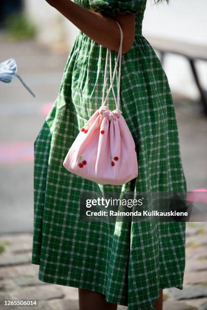 Guest outside Malaikaraiss wearing green checked dress, pink bag with cherries and a hat during Copenhagen fashion week SS21 on August 10, 2020 in...