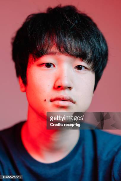 studio shot portrait of young man lit by red neon light - asian man studio shot stock pictures, royalty-free photos & images