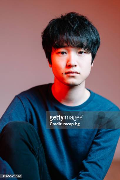 studio shot portrait of young man lit by red neon light - young male model stock pictures, royalty-free photos & images