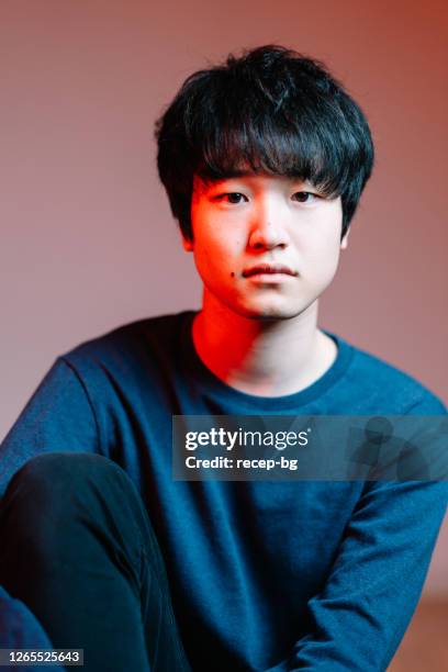 studio shot portrait of young man lit by red neon light - studio head shot serious confident looking at camera imagens e fotografias de stock