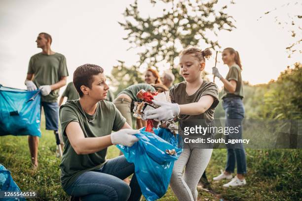 mother and daugther collecting garbage from the park - disability collection stock pictures, royalty-free photos & images