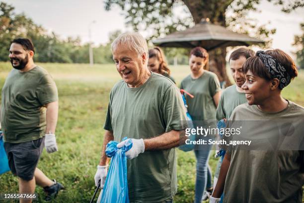 gruppe von freiwilligen, die nach der reinigung in der natur gemeinsam abreisen - soziales engagement stock-fotos und bilder