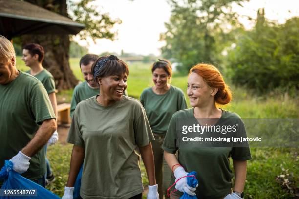gelukkige vrijwilligers bonding na milieu-opruiming op openbaar park - volunteer stockfoto's en -beelden