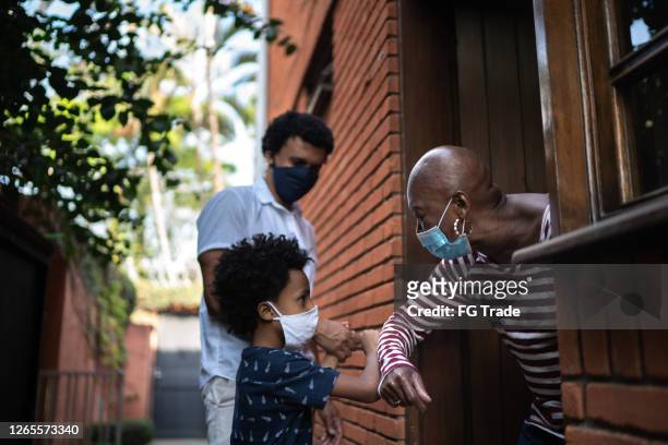 grandmother and grandson using elbow greeting - black family reunion stock pictures, royalty-free photos & images