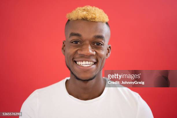ritratto di uomo di colore casual di 25 anni sorridente alla telecamera - capelli rasati su un lato foto e immagini stock