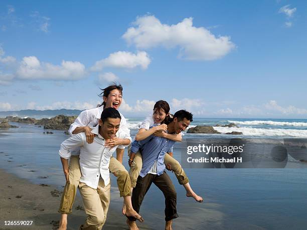 two couples who compete happily on a beach - asian man barefoot foto e immagini stock