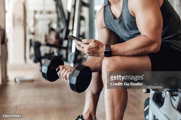 spierjonge mens opleiding bij gymnastiek met slimme telefoon - fitness man gym stockfoto's en -beelden