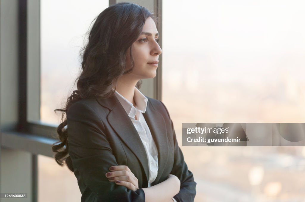 Young businesswoman looking throughwindow in a modern office