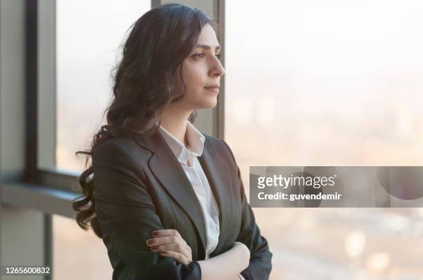 young businesswoman looking throughwindow in a modern office - west asia stock pictures, royalty-free photos & images