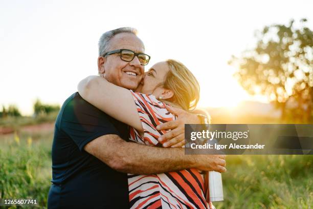 vader en dochter die elkaar bij zonsondergang op het platteland houden - father and grown up daughter stockfoto's en -beelden