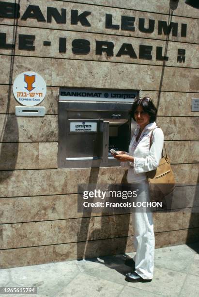 Une femme retire de l'argent à un distributeur de banque à Tel Aviv en juillet 1977, Israël