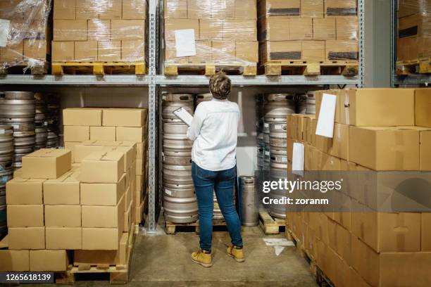 weibliche lagerleiterin mit checkliste, die brauereibedarf prüft - bierkasten stock-fotos und bilder