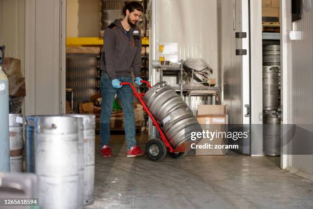 brauer schiebt wagen mit aluminiumfässern - beer cart stock-fotos und bilder