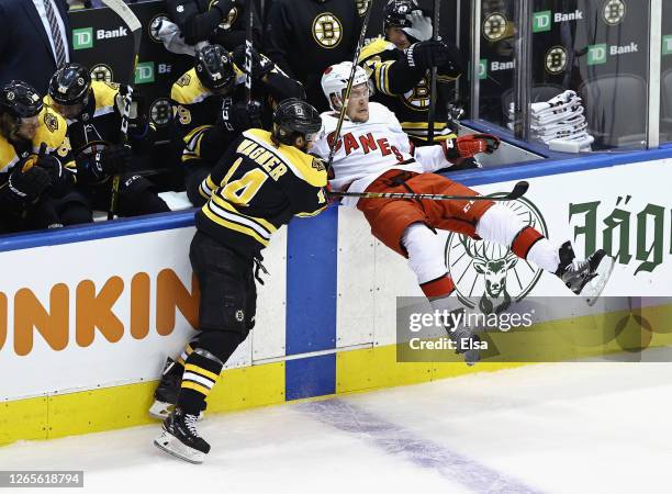 Chris Wagner of the Boston Bruins checks Jake Gardiner of the Carolina Hurricanes into the boards during the first period in Game One of the Eastern...