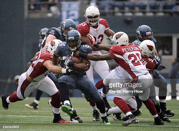 Marshawn Lynch of the Seattle Seahawks breaks through a hole between Patrick Peterson and Stewart Bradley of the Arizona Cardinals and Crat...
