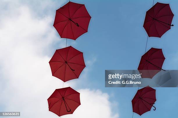 red umbrellas flying in blue sky - flyingconi stock pictures, royalty-free photos & images