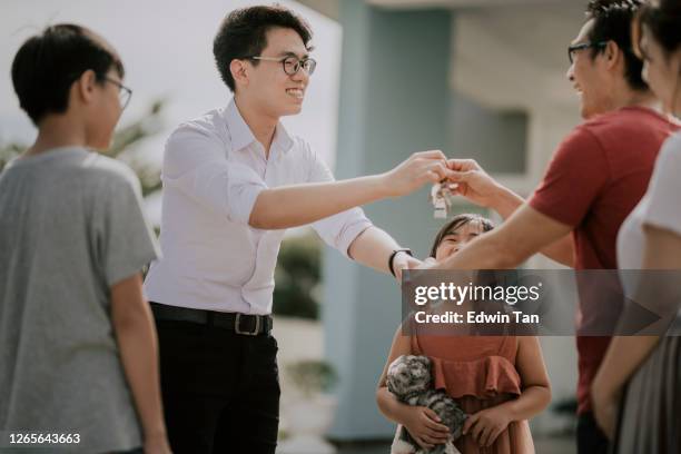 eine asiatische chinesische familie zieht in ein neues haus und erhielt den hausschlüssel von immobilienmakler - agent and handing keys stock-fotos und bilder