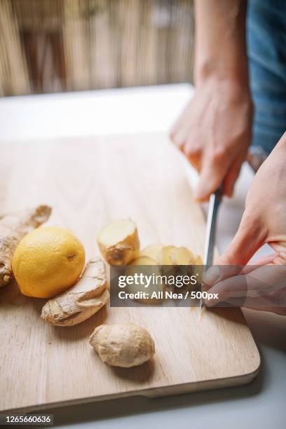 cropped hands of woman cutting ginger on board in kitchen, lleida, spain - ginger stock pictures, royalty-free photos & images