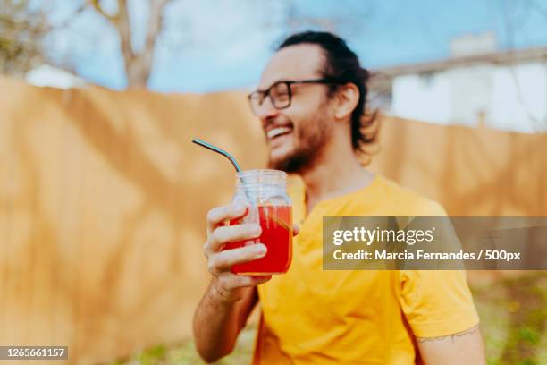 smiling young man drinking juice from eco-friendly glass with reusable straw, victoria, canada - metal drinking straw stock pictures, royalty-free photos & images