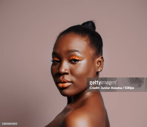 beauty portrait of black adult woman with orange eyeshadow - trucco per il viso foto e immagini stock