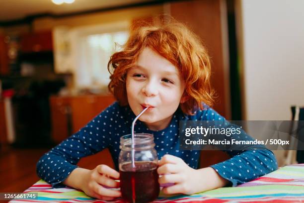 cute boy drinking juice while sitting at table, victoria, canada - metal straw stock pictures, royalty-free photos & images