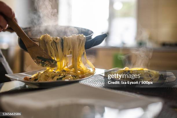 caucasian adult serving homemade pasta for dinner during the evening, inwad, poland - sacada fotografías e imágenes de stock