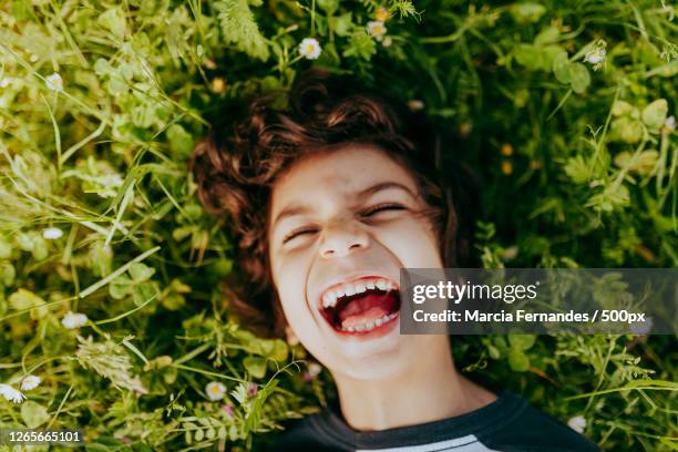 young caucasian brazilian boy lying on the ground and laughing during the summer, victoria, canada - victoria canada stock-fotos und bilder
