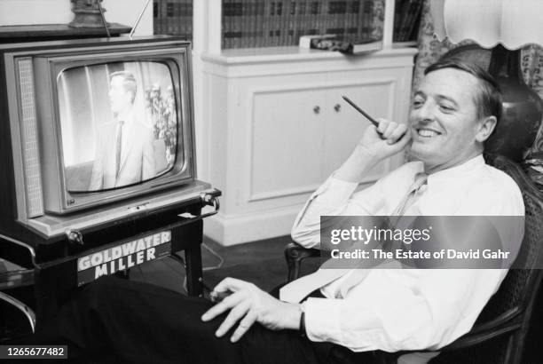 American public intellectual, commentator, and author William Frank Buckley, Jr. Sits at home in front of a TV set, while smoking a cigar, to view...