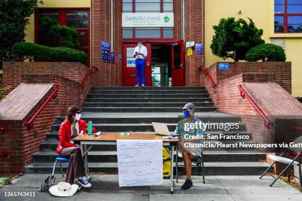 Administrators wait for parents to check in to grab bagged lunch and supplies outside of Sankofa Academy on the first day of school on Monday, Aug....