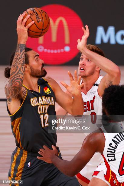 Steven Adams of the Oklahoma City Thunder grabs a rebound against Meyers Leonard and Solomon Hill of the Miami Heat during the third quarter at Visa...