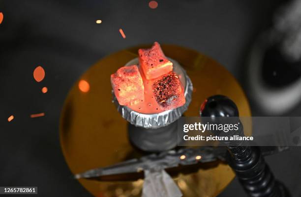 June 2023, Baden-Württemberg, Sindelfingen: Pieces of coal for heating the tobacco lie on a hookah water pipe in a hookah bar. Shisha bars are...