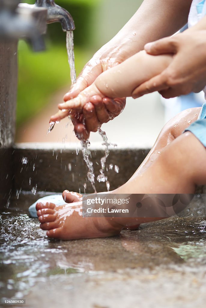 Mother washing baby's hands and feet