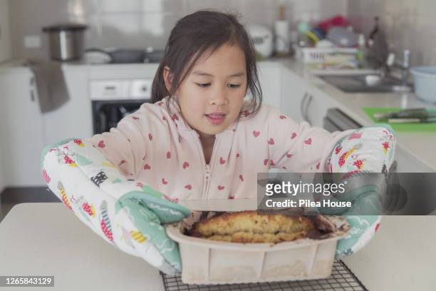 mixed race asian girl baking independently at home - banana loaf stock pictures, royalty-free photos & images