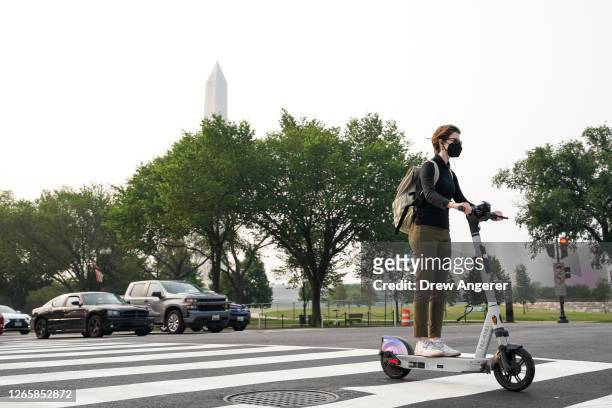 Woman wears a face covering as she rides her scooter along Constitution Avenue on June 29, 2023 in Washington, DC. The Washington DC region is under...