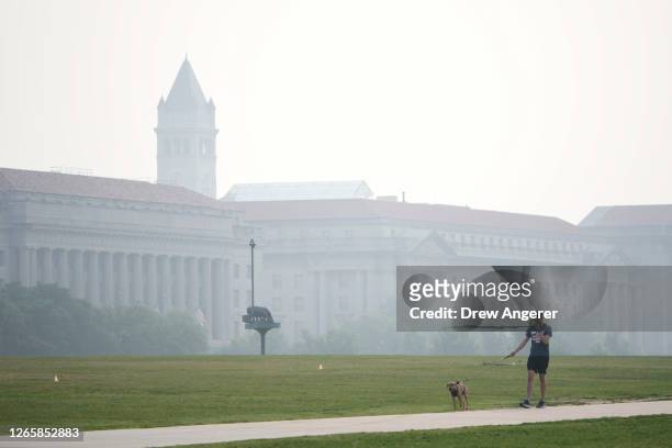 Man walks his dog as wildfire smoke casts a haze over the National Mall on June 29, 2023 in Washington, DC. The Washington DC region is under a "Code...
