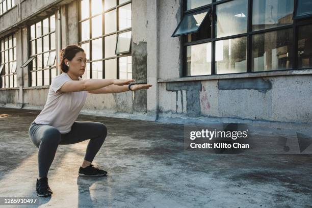 asian woman doing squats while listening to something - squatting position 個照片及圖片檔