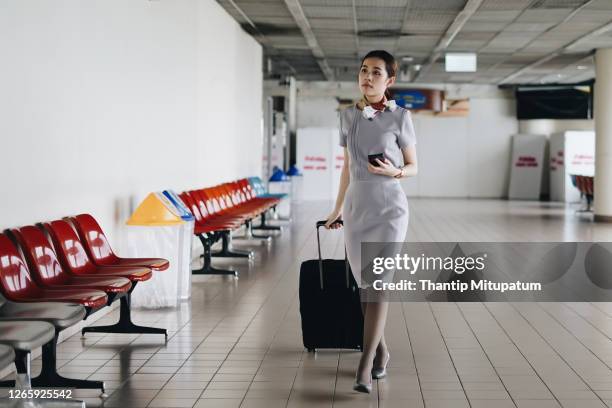 portrait of beautiful hostess in airport with mobile phone. - airline service stock pictures, royalty-free photos & images