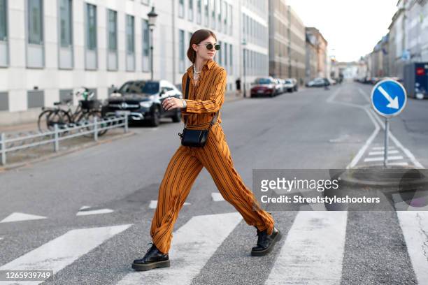Influencer Jacqueline Zelwis, wearing curry colored suit with black stripes by Copenhagen Muse, black boots by Dr. Martens, a black mini bag by Lala...