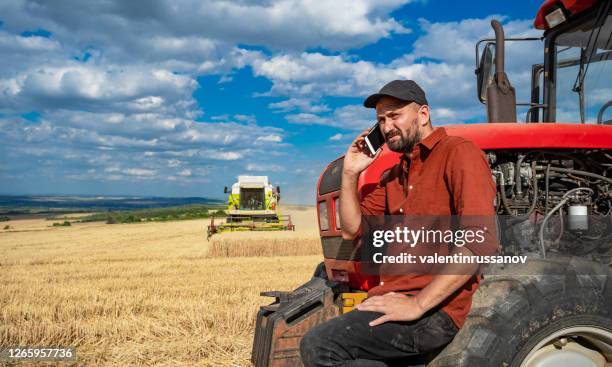 farmer controlled harvest in his field and talking on a smart phone - farmers insurance stock pictures, royalty-free photos & images