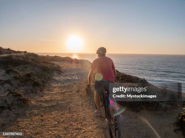 mountain biker riding on the edge of a cliff at sunset - algarve stock pictures, royalty-free photos & images