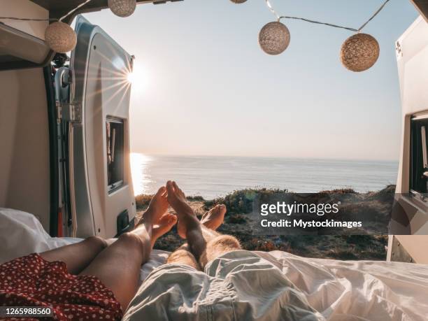 paar dat bij de rug van een bestelwagen ligt dat oceaan, persoonlijk perspectief bekijkt - campervan stockfoto's en -beelden