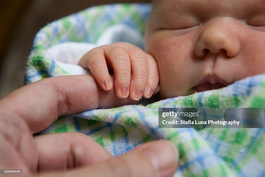 Newborn baby grasping finger