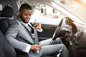 Handsome black businessman fasten seat belt in his car