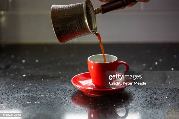 pouring turkish coffee from an ibrik to a bright red coffee cup - ジェズベ ストックフォトと画像