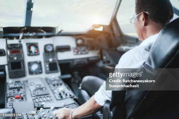 male pilot sitting in an airplane cabin flying. - airline pilot imagens e fotografias de stock