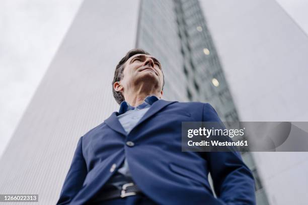 confident mature businessman standing in front of an office tower in the city - inquadratura estrema dal basso foto e immagini stock